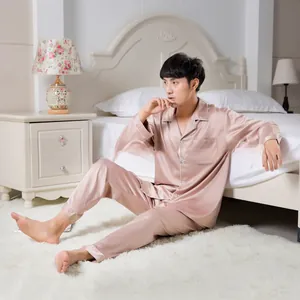 Close-up of men's satin pajama set with contrast piping in a cozy bedroom setting