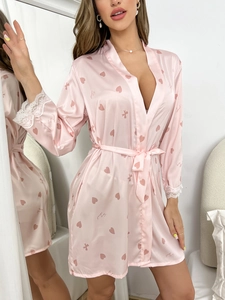Détail d'un peignoir en satin rose avec imprimé cœur et dentelle blanche aux manches