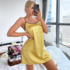 Camisón de satén amarillo con tirantes negros y bordado de corazón en ambiente hogareño