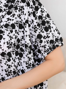 Detail of short sleeve with elastic ruffle cuff and black floral print on white fabric