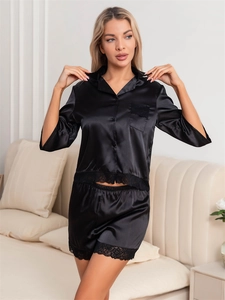 Detailed close-up of the delicate black lace trim on black satin pajama sleeve and hem