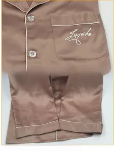 Detailed view of satin pajama pocket with Layeiko embroidery and premium pearl buttons