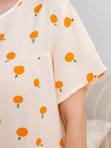 Detailed view of the bubble cotton fabric with orange prints and neck piping of the sleepwear