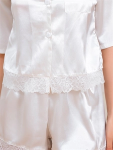 Close-up of white ice silk pajama set featuring delicate lace trim and satin texture