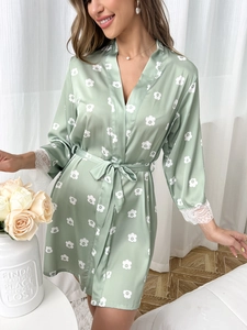 Détails des poignets en dentelle et du motif floral sur le peignoir en satin de soie vert