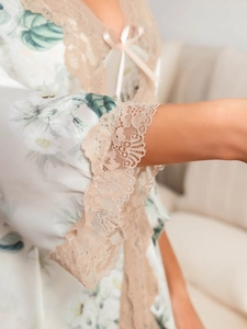Détail de poignets de pyjama en soie avec dentelle beige et motif floral chic