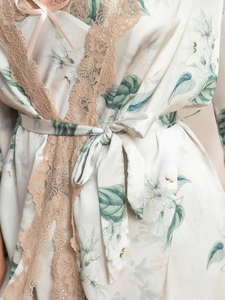Détail du peignoir en satin fleuri avec bordure en dentelle rose et nœud délicat