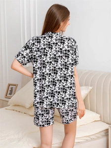 Rear view of women's short-sleeve floral pajama set in a cozy bedroom setting