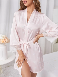 Détail du peignoir rose en soie avec motif floral et dentelle délicate aux manches