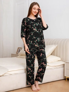Detail of floral women's pajama set featuring pink roses on black fabric and button top
