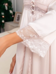 Gros plan sur la manche du peignoir en satin rose avec dentelle blanche et bordure cil