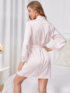 Détail du peignoir en satin rose avec motif floral et dentelle délicate sur les manches