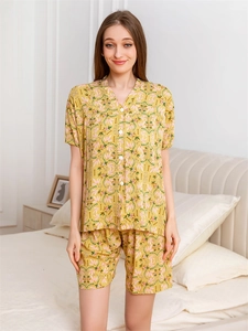 Detail of yellow rayon pajamas with pink leaf print and white buttons in a bedroom setting