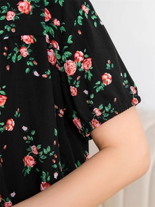Detailed view of elastic cuffs and red rose floral print on black rayon pajamas