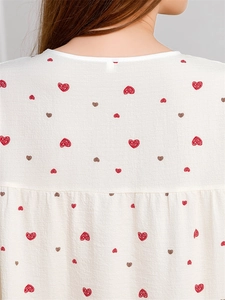 Detail of crew neckline and heart print on cream fabric with subtle pleats