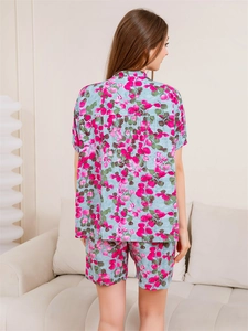 Rear view of loose fit floral pajama set featuring pink flower clusters on light blue