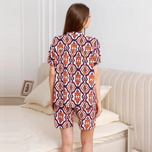Women's pajama set featuring geometric print short sleeve shirt and shorts in a bedroom