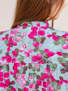 Detail of V-neck summer pajamas showing light blue fabric with pink floral leaf patterns