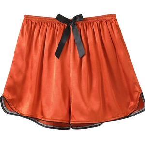 Close-up of rust orange ice silk lounge shorts with black bow and curved hem detail