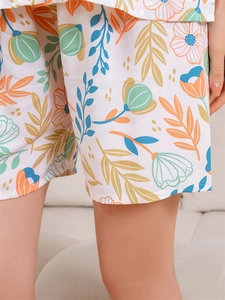 Detail showing tropical floral prints and hem stitching on white cotton pajama shorts