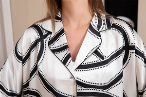 Détail du haut de pyjama à col en V avec imprimé géométrique noir sur satin blanc