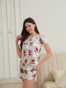Détail de l'ensemble pyjama soyeux avec imprimé floral rouge sur tissu blanc satiné