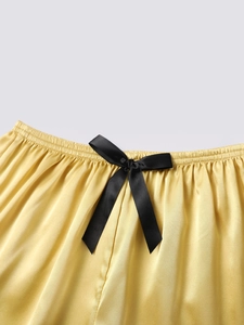 Detailed macro view of yellow silk shorts featuring an elastic waist and black bow