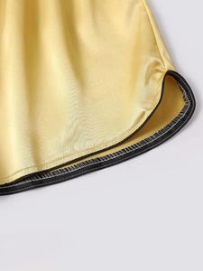 Detail of yellow silk shorts featuring black piping and precise white contrast stitching