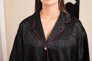 Détail d'un haut de pyjama en soie noire avec motif léopard jacquard et liseré rouge élégant