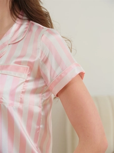 Close-up of pink striped satin pajama top with classic lapel and white piping detail