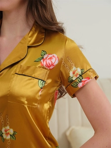 Detail of silk satin pajama top with pink rose prints, V-neck collar and black piping edge