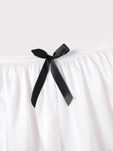 Detailed macro of a black satin bow on elastic waist ice silk shorts for women