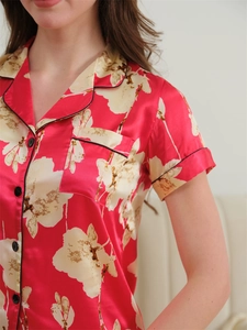 Close-up of red silk pajama top with white floral print and black piped detail