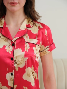 Close-up of red floral ice silk pajama top with black contrast piping and notched collar