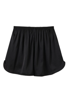 Detail showing elastic high waist and white contrast trim on black silk satin shorts