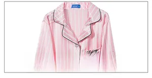 Detailed view of striped silk pajamas with contrast piping and delicate chest embroidery