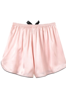 Detailed view of pink silk satin sleep shorts featuring a black bow and contrast trim