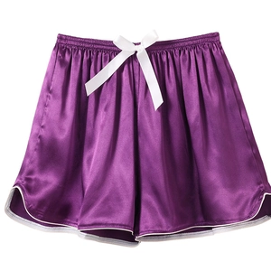 Detail of purple satin sleep shorts featuring a white silk bow and contrast piping edges