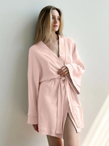 Detail of pink waffle knit women's bathrobe showing textured fabric and adjustable waist belt