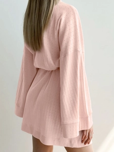 Detailed macro view of the light pink knit waffle texture and ribbed sleeve cuff on bathrobe