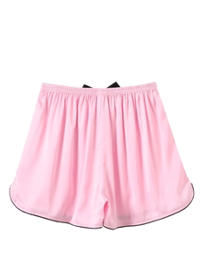 Detail of silk pajama shorts featuring pink satin fabric with black bow and lace trim