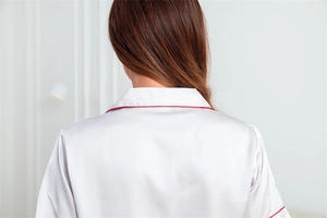 Détail de l'encolure du pyjama en soie glacée blanche avec liseré rouge élégant
