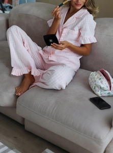 Detail of pink plaid cotton pajamas set featuring ruffled edges and a button-up collar