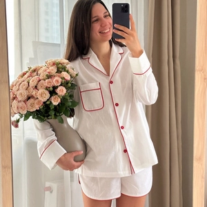 Women's two-piece white cotton pajama set with red piping and button-up long sleeves