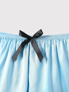 Detail of light blue silk pajamas shorts with elastic waist and black satin bow accent