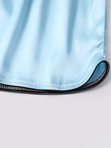 Detailed macro view of light blue ice silk fabric with black contrast piping and curved hem