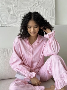 Detail view of pink plaid pajama set featuring ruffle cuffs and soft cotton fabric texture