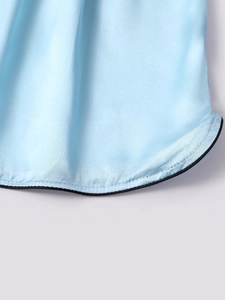 Close-up of light blue ice silk sleep shorts featuring smooth satin and black contrast piping