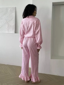 Detail of pink gingham pajama set featuring ruffled cuffs and soft cotton fabric texture