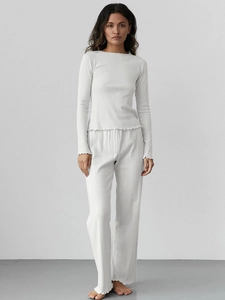 Detail of white ribbed knit pajama set with ruffle hem edges and comfortable wide leg pants